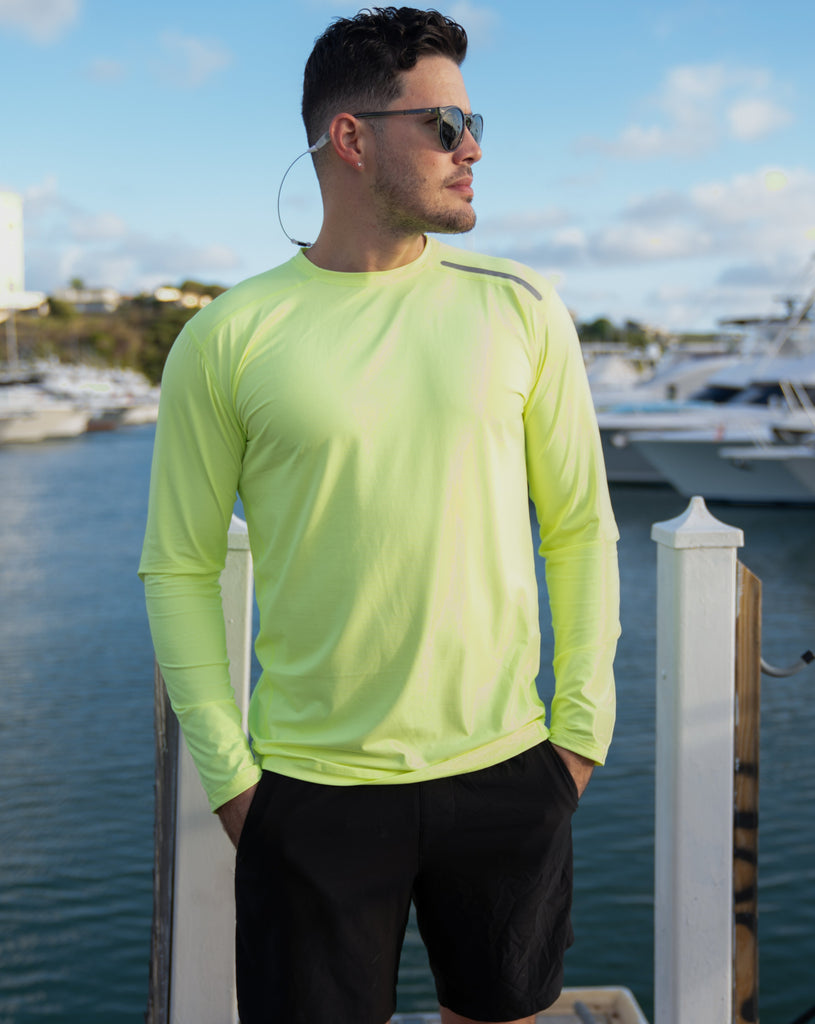 Man standing in marina wearing long sleeve jet tee shirt in neon yellow. (Style 12002) - BloqUV