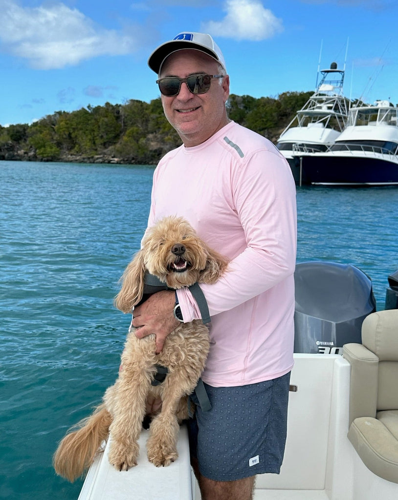 Man standing with dog in boat wearing long sleeve jet tee shirt in tickle me pink. (Style 12002) - BloqUV