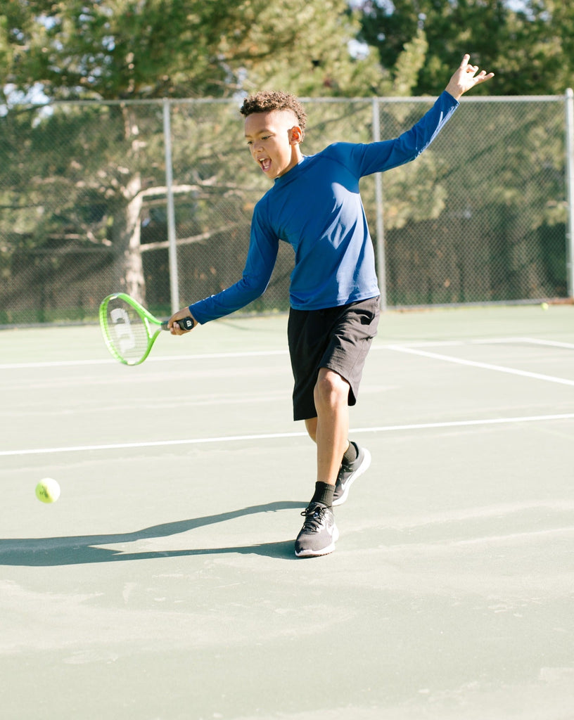 Boy playing tennis wearing navy sun protective top. (Style 1005K) - BloqUV