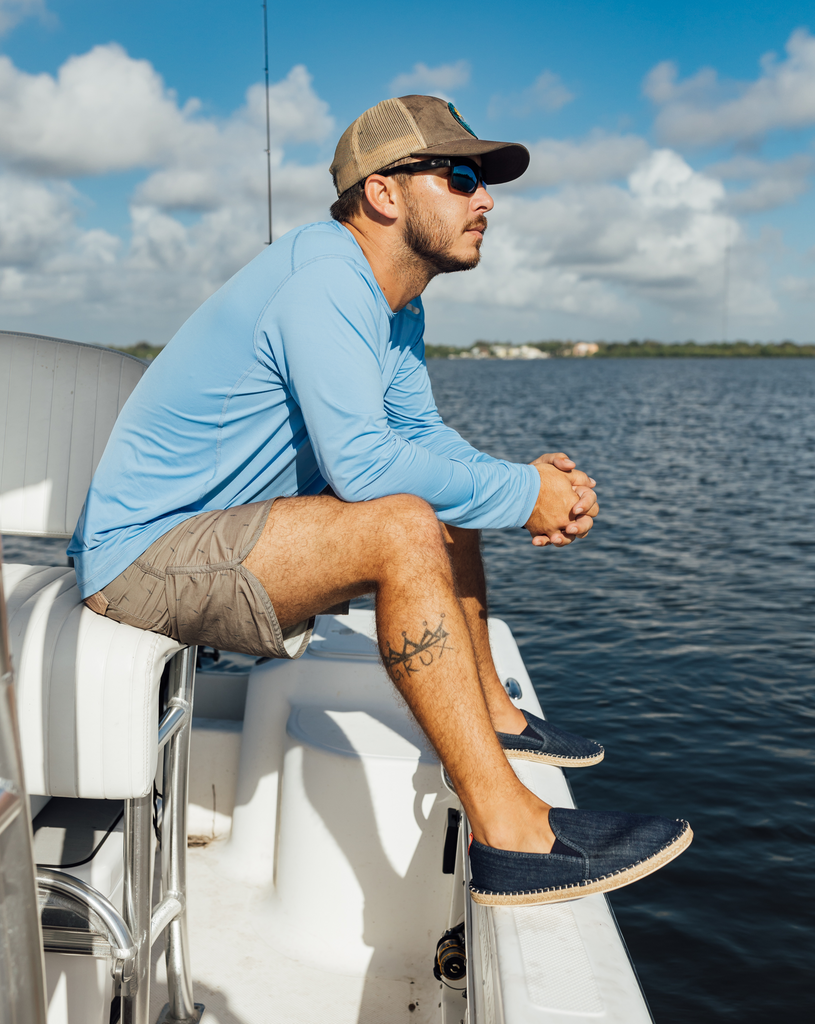 Man  sitting on the side of the boat wearing long sleeve jet tee shirt in indigo blue. (Style 12002) - BloqUV