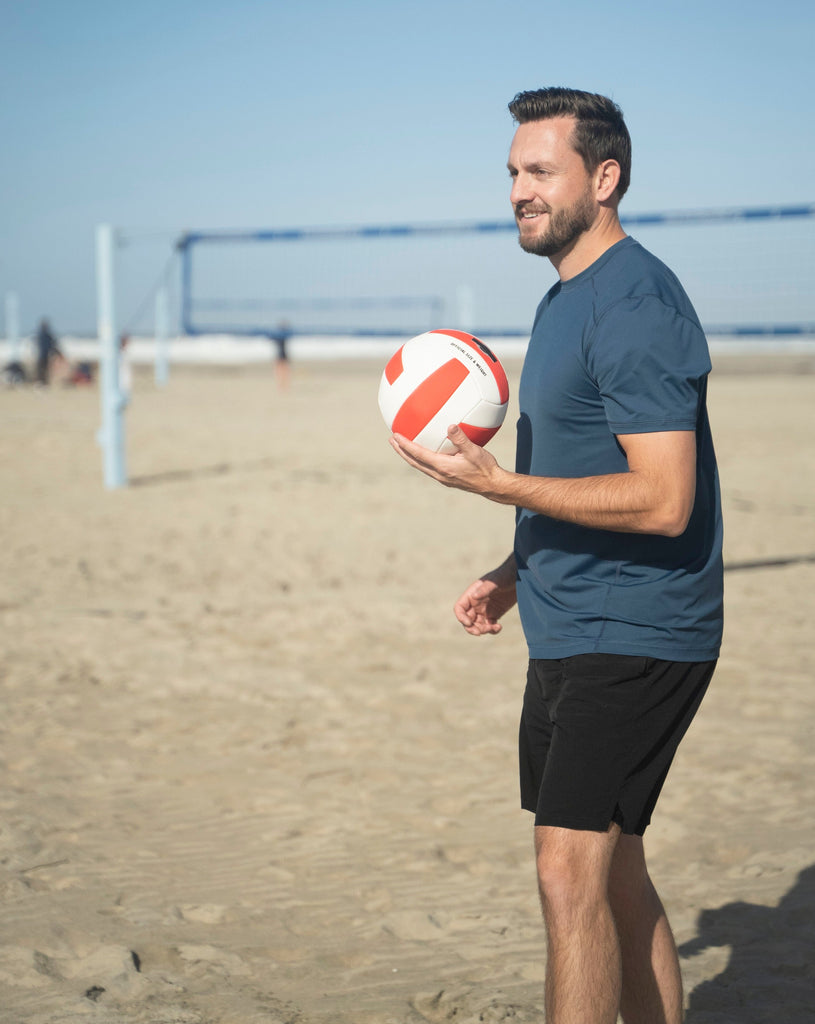Man at the beach playing volleyball wearing short sleeve crew shirt in midnight blue. (Style 11002) - BloqUV