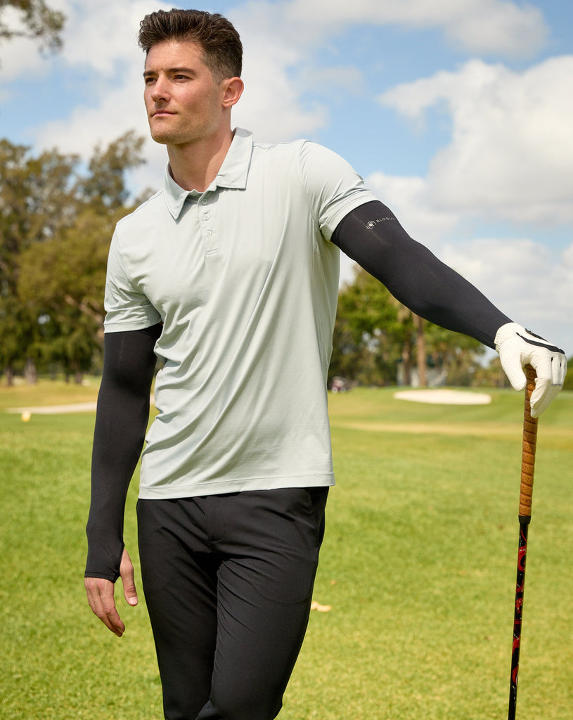 Man standing at the golf course wearing black color unisex sleeves with short sleeve soft grey jet tee. (Style 5005) - BloqUV