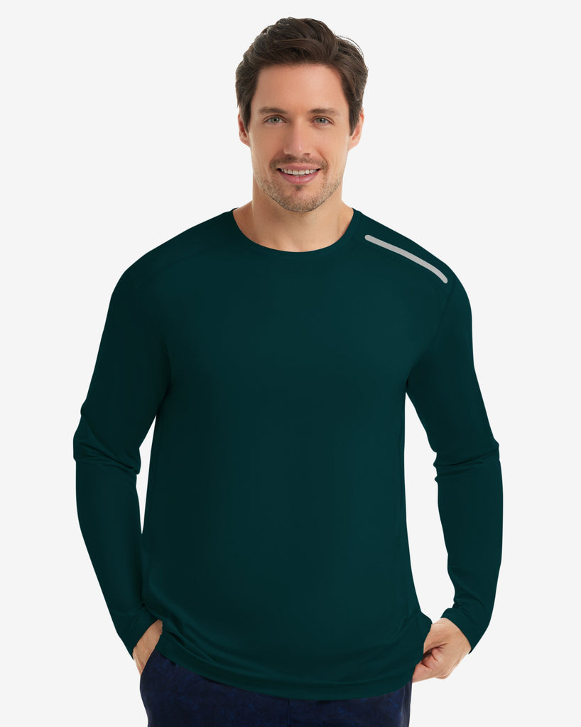 Man wearing a green long-sleeve athletic shirt and navy shorts on a white background