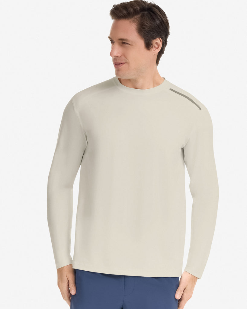 Man wearing a beige long-sleeve shirt and blue shorts on a white background