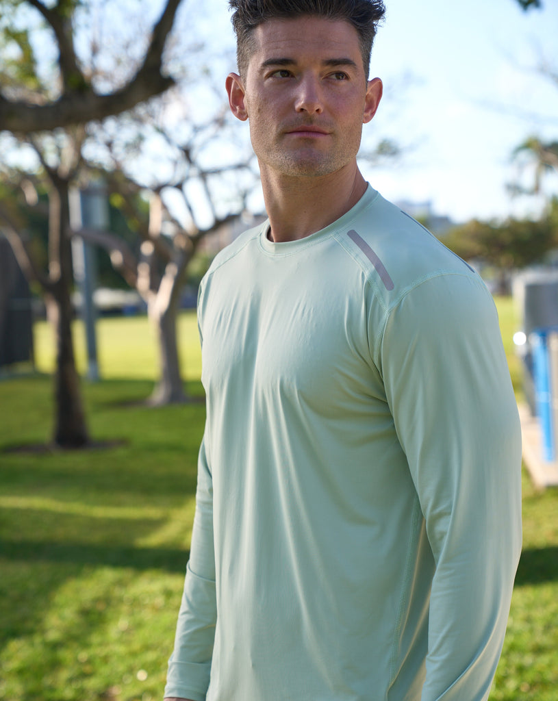Man at the park wearing long sleeve jet tee shirt in sage. (Style 12002) - BloqUV
