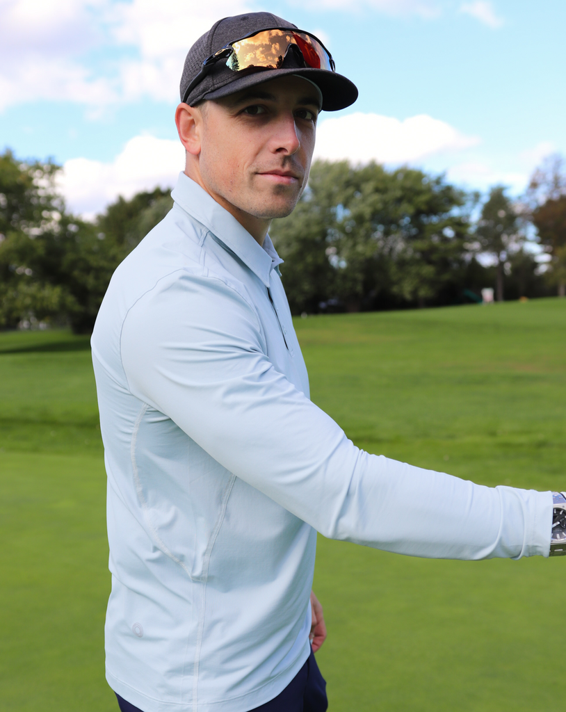 Man standing in golf filed wearing long sleeve collared shirt in soft grey. (Style 12004) - BloqUV