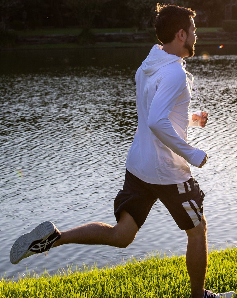 Man running wearing white unisex long sleeve hoodie shirt. (Style 12007) - BloqUV
