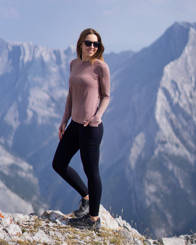 Woman standing on a mountain peak with snow-capped mountains in the background