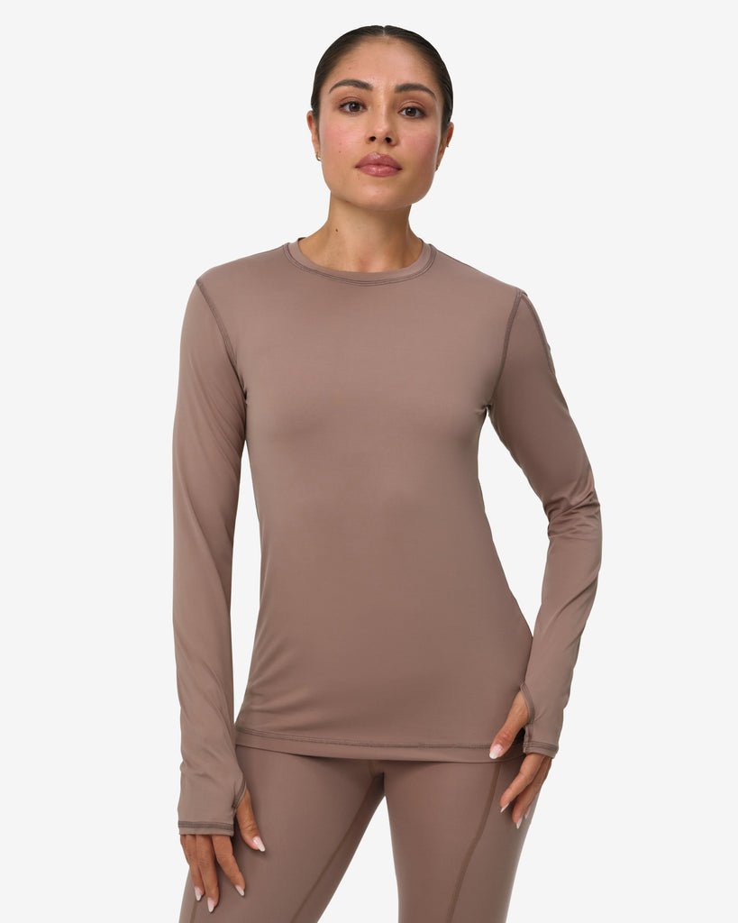Woman wearing a brown long-sleeve top and pants on a white background