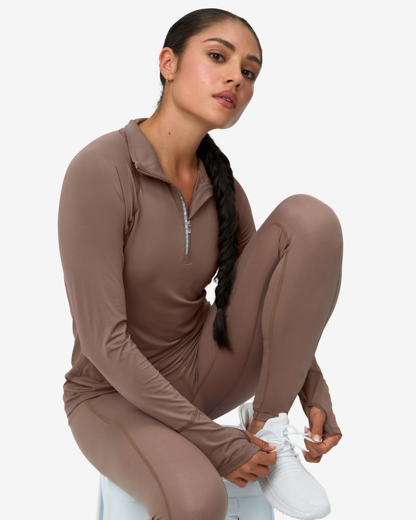 Woman wearing a brown athletic outfit with white sneakers on a white background