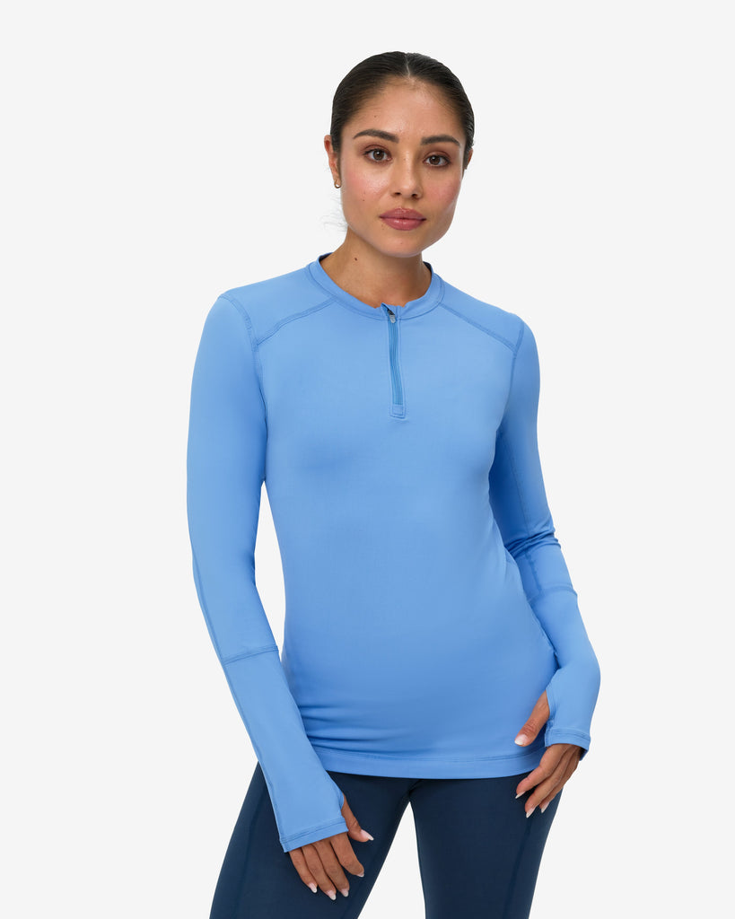 Woman wearing a blue long-sleeve top with a white background