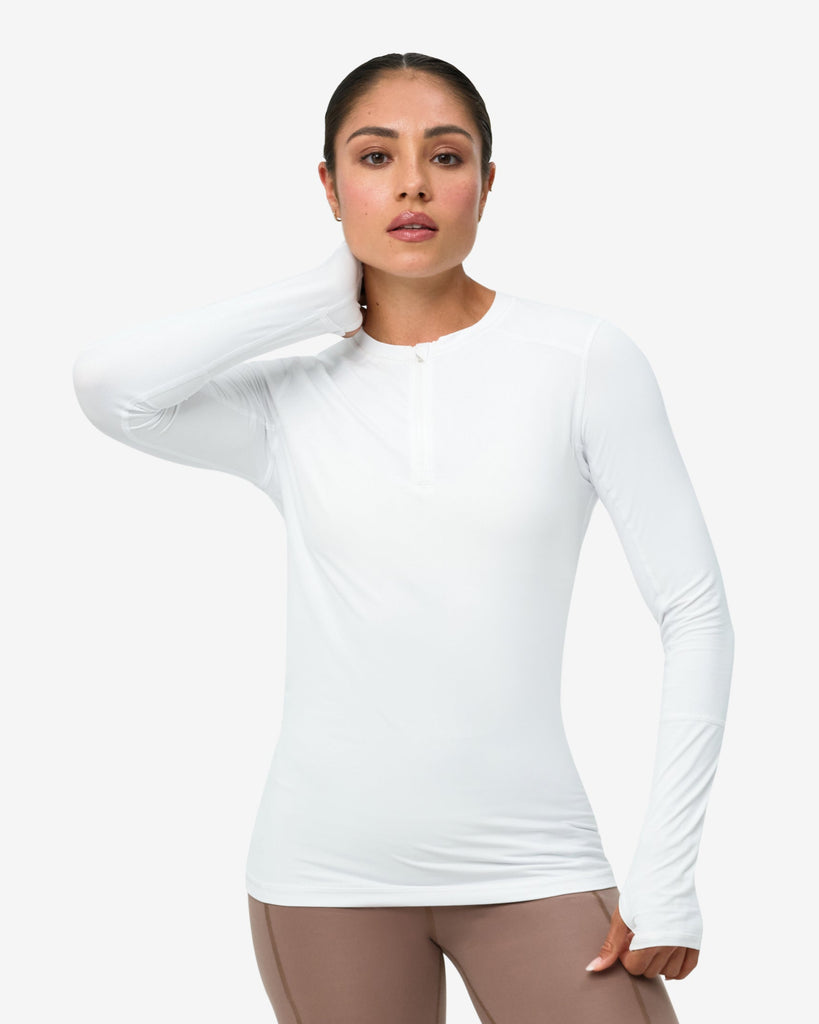 Woman wearing a white long-sleeve top and brown leggings on a white background