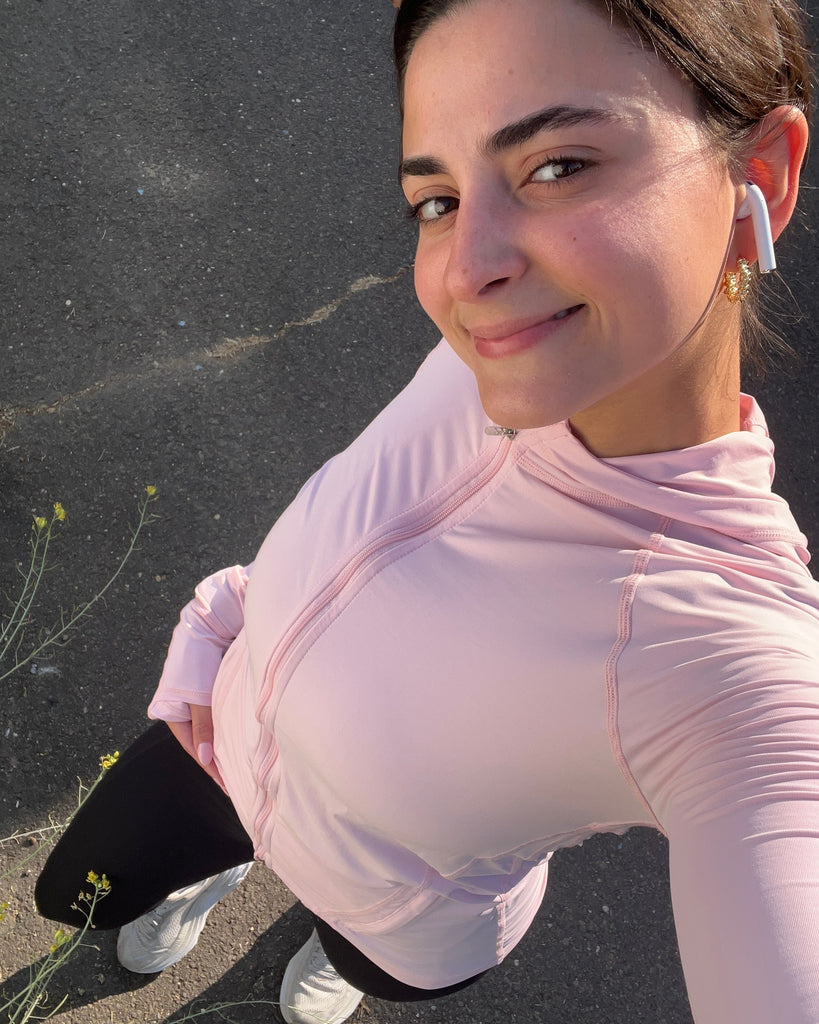 Woman in a light pink athletic outfit standing on a dark surface.