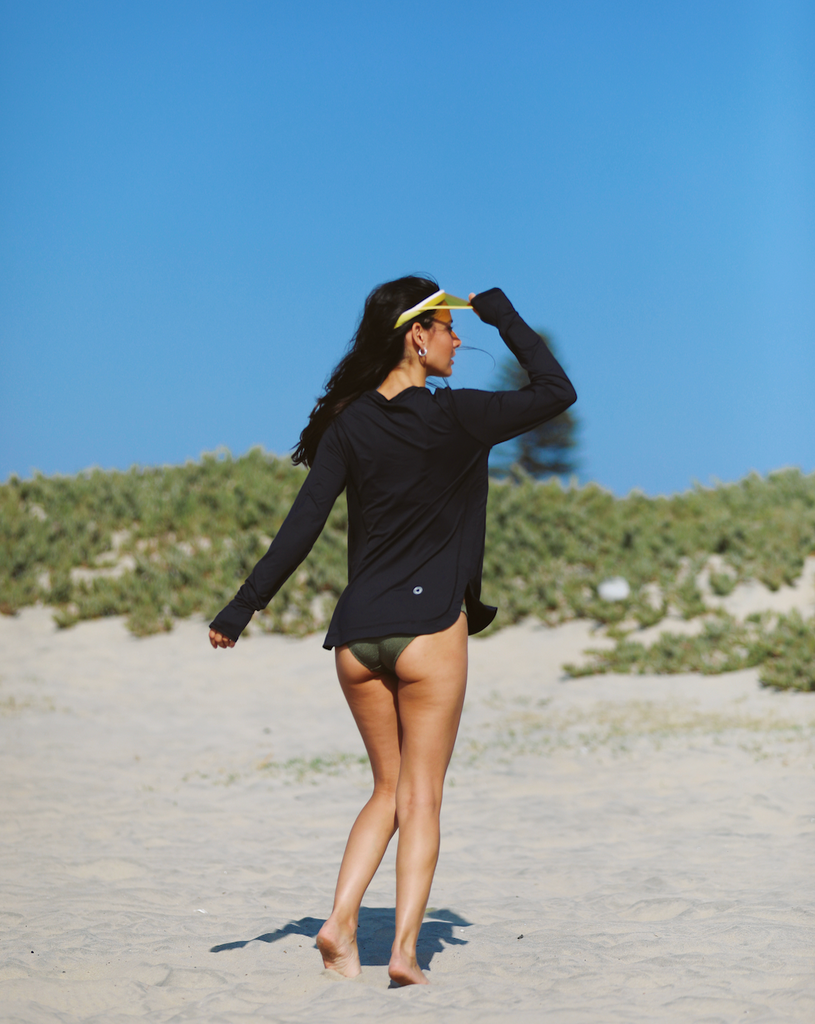 Women walking on the sand wearing black relaxed scallop top with swimsuit. Picture shows back of shirt. (Style 2015) - BloqUV