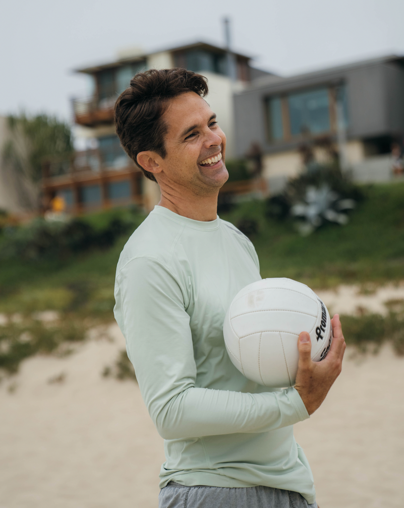 Man holding volleyball wearing long sleeve jet tee shirt in sage. (Style 12002) - BloqUV