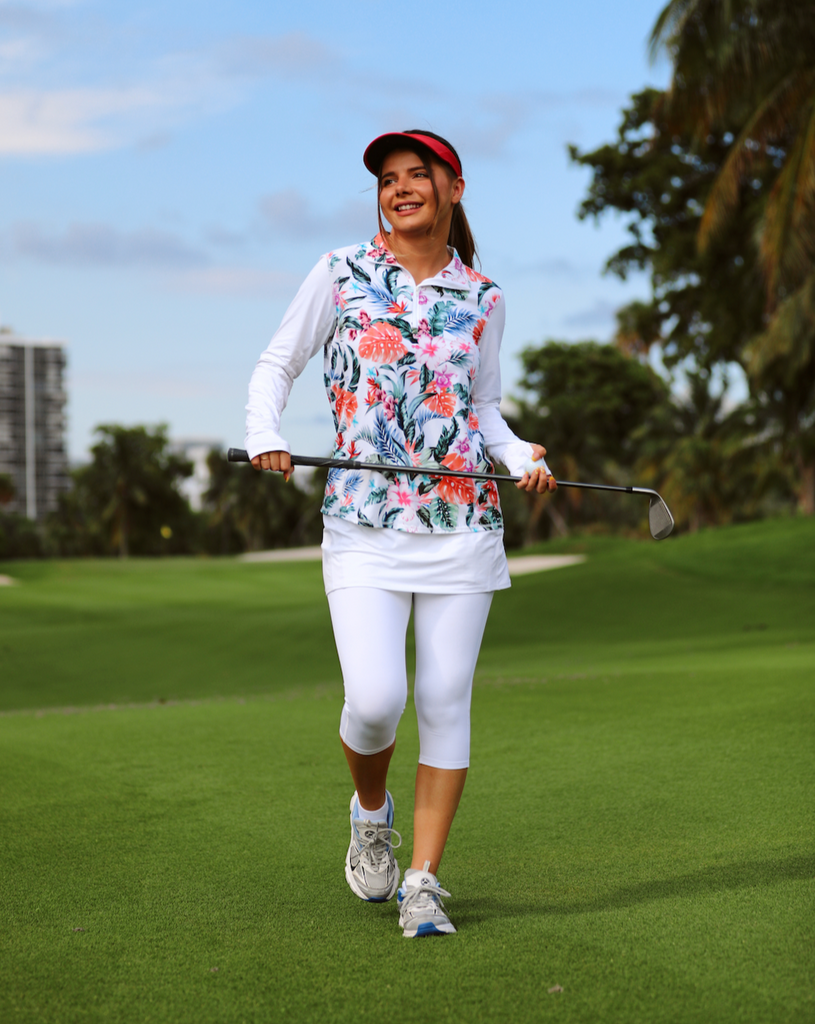 Women playing golf wearing printed white top with Hawaiian print long sleeve relaxed mock zip top with white capri skort bottom. (Style 3002J) - BloqUV