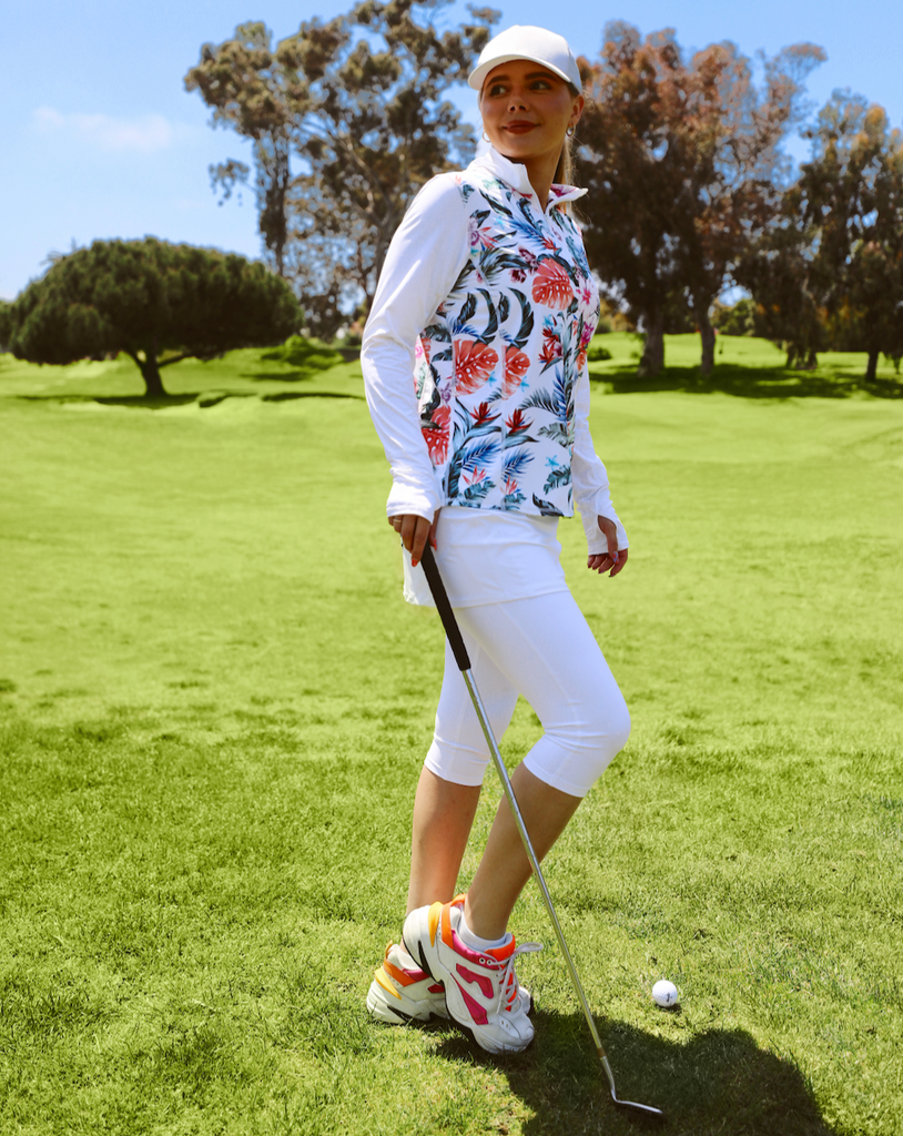 Women playing golf wearing printed white top with Hawaiian print long sleeve relaxed mock zip top with white capri skort bottom. (Style 3002J) - BloqUV