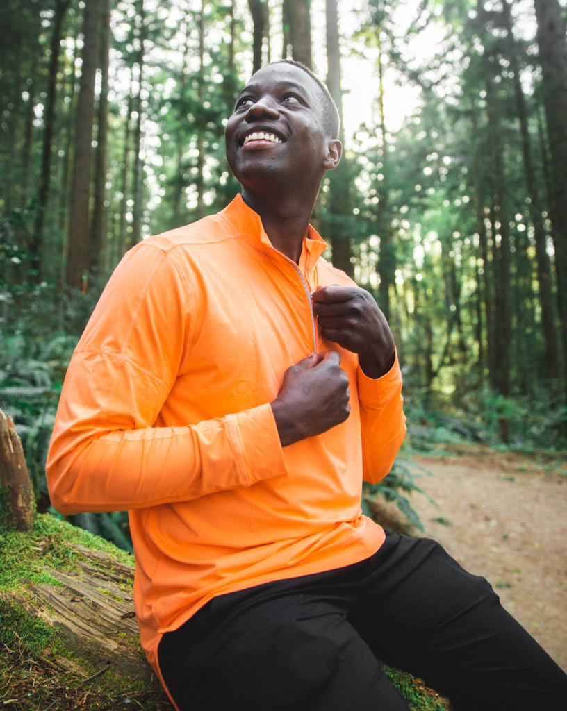 Man sitting in the forest at the beach wearing long sleeve mock zip shirt in tangerine (Style 12001) - BloqUV