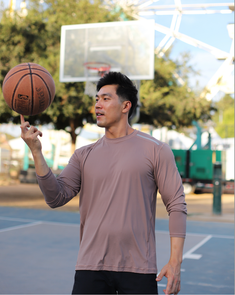 Man holding a basketball on an outdoor court with a Ferris wheel in the background