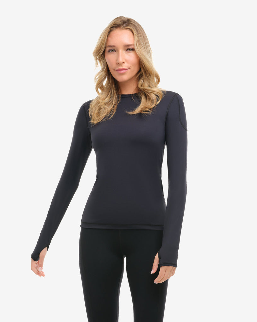 Woman wearing a black long-sleeve top and leggings on a white background
