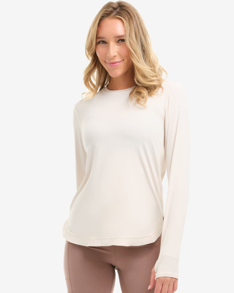 Woman wearing a white long-sleeve top and beige shorts on a white background