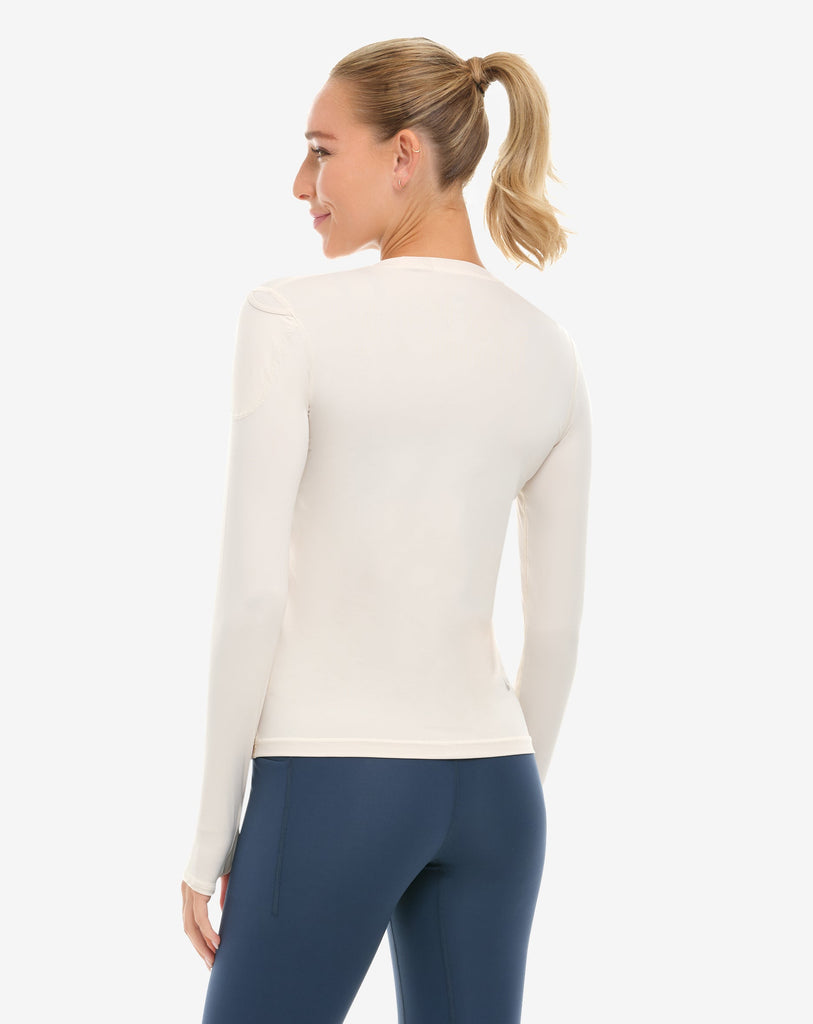 Woman wearing a white long-sleeve top and blue leggings on a white background