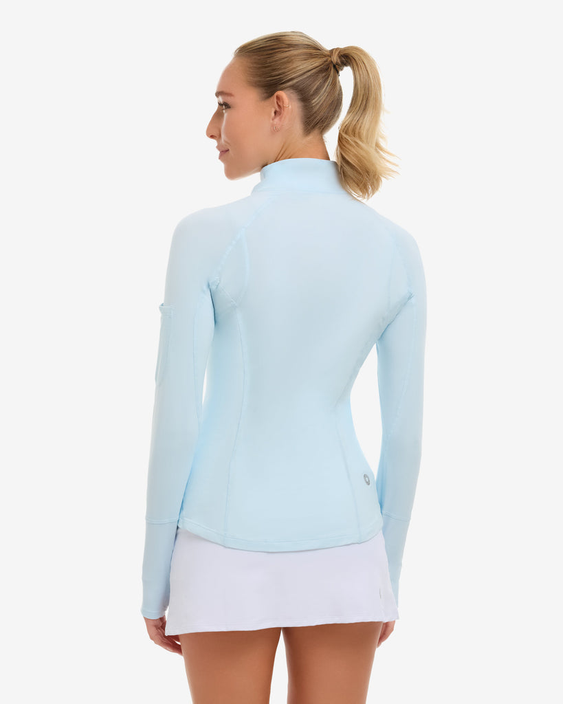 Woman wearing a light blue long-sleeve top and white skirt on a white background