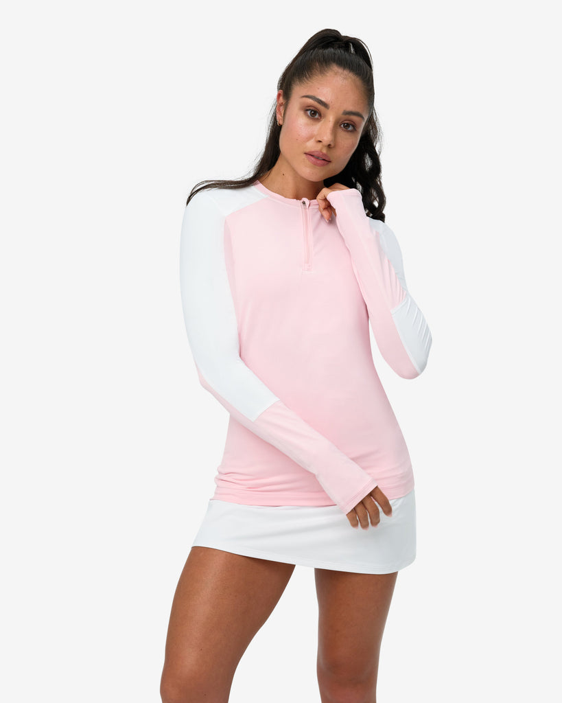 Woman wearing a pink and white long-sleeve top with a white skirt on a white background