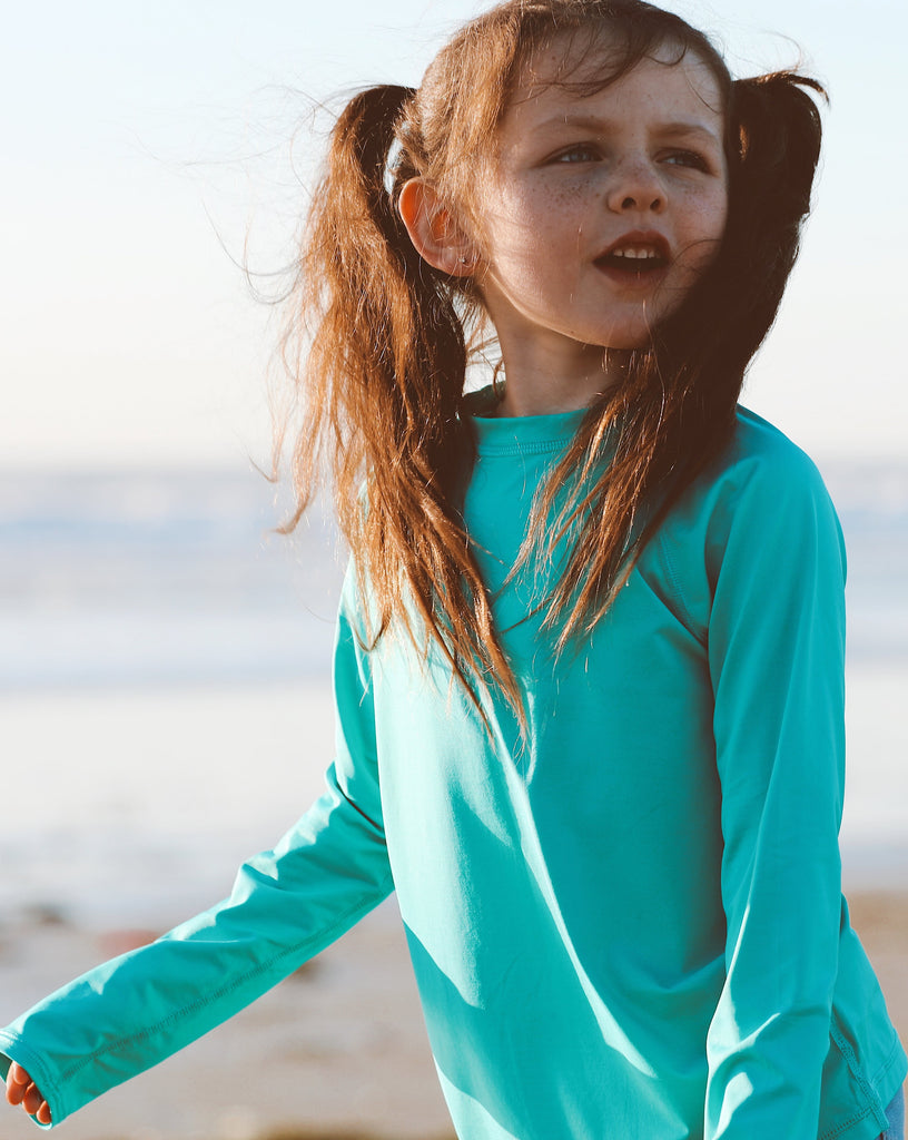 Girl wearing carribbean blue color top while playing at the beach. (Style 1005K) - BloqUV