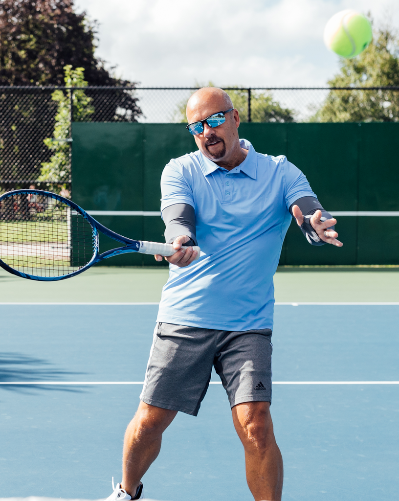 Man playing tennis wearing short sleeve polo shirt in indigo with smoke sun sleeves. (Style 11004) - BloqUV
