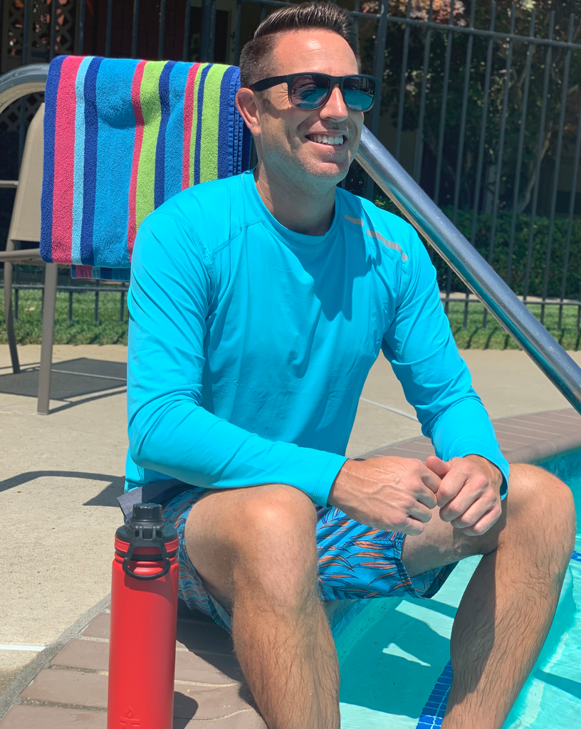 Man sitting by the pool wearing long sleeve jet tee shirt in light turquoise. (Style 12002) - BloqUV