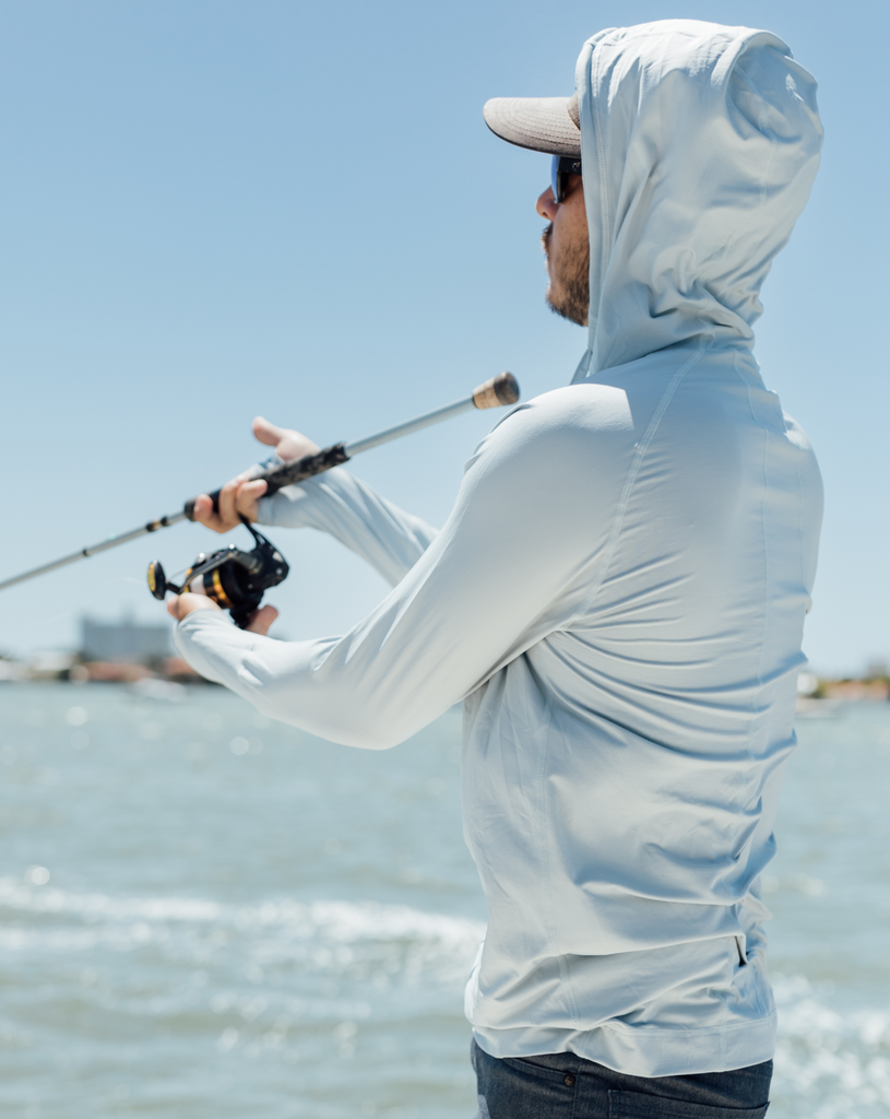 Man fishing wearing soft grey unisex long sleeve hoodie shirt. Picture shows hoodie over the head. (Style 12007) - BloqUV