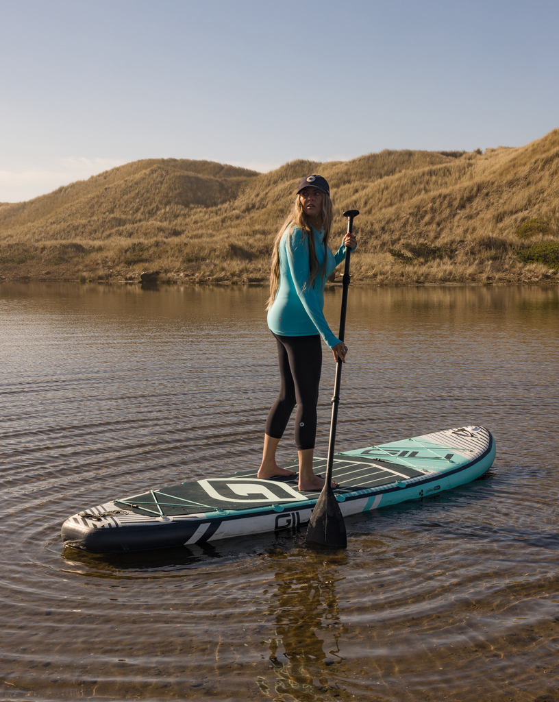 Women paddle boarding wearing compression capri leggings in black with light turquoise top. (Style 6103) -BloqUV