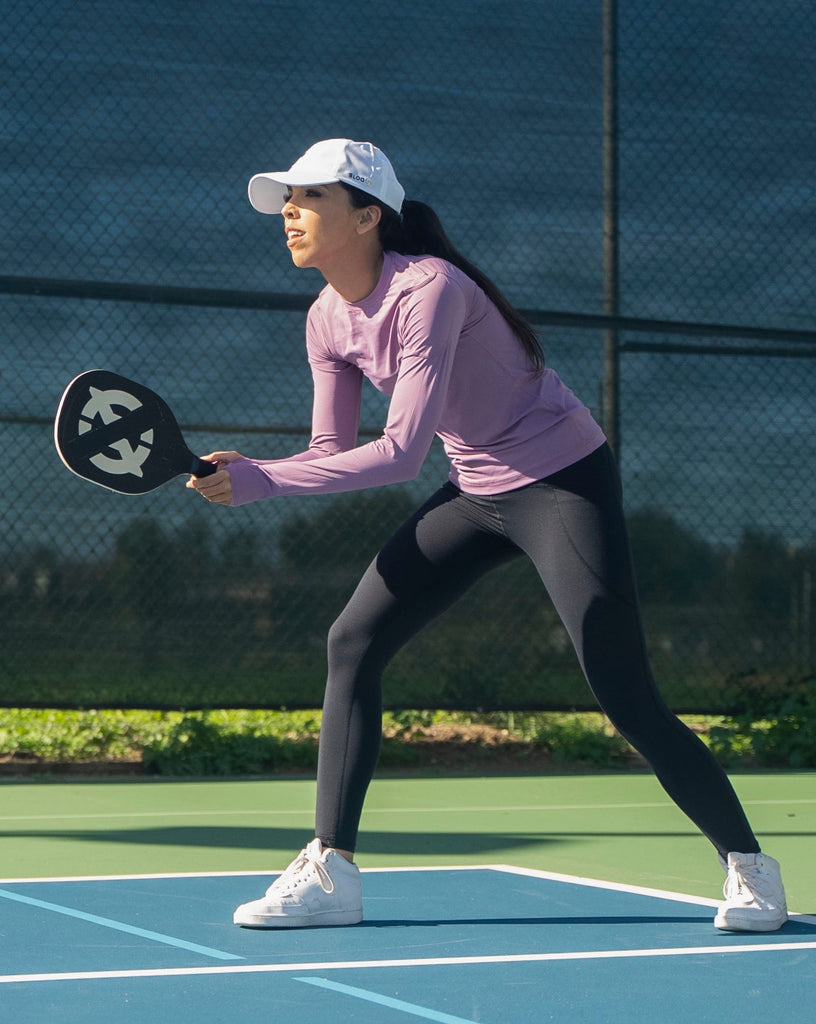 Women playing tennis wearing sage long sleeve 24/7 shirt with black tights. (Style 2001) - BloqUV