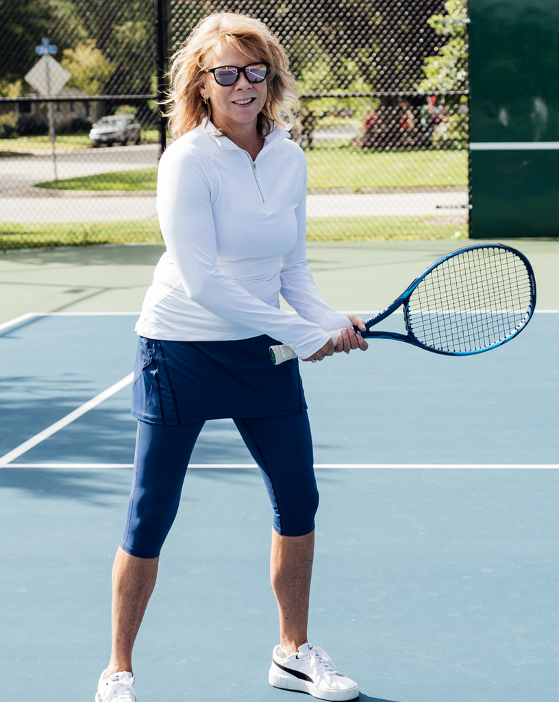 Women playing tennis wearing white mock zip long sleeve top with navy skorts capri. (Style 3001) - BloqUV