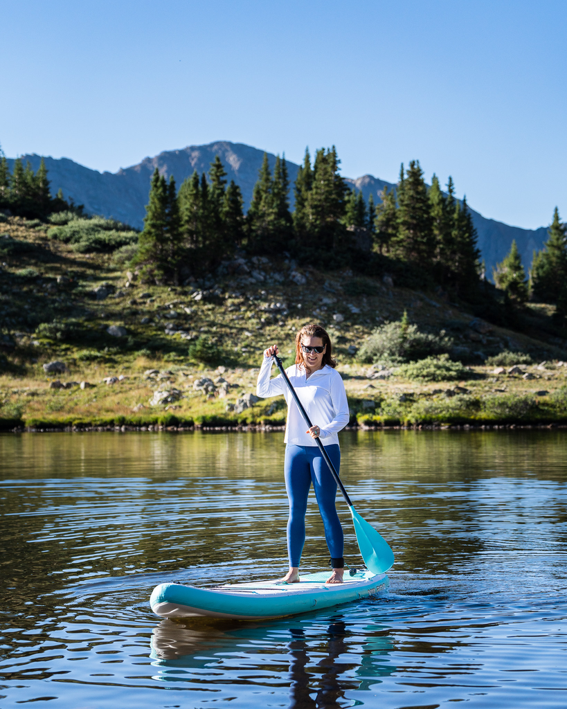 Women paddle boarding wearing white relaxed mock zip top with navy tights. (Style 3002) - BloqUV