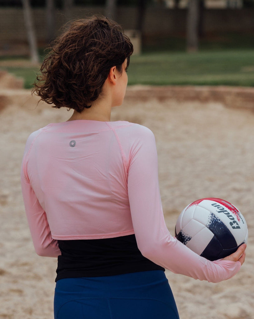 Women playing volleyball wearing tickle me pink crop top and black tank underneath. (Style 3002) - BloqUV