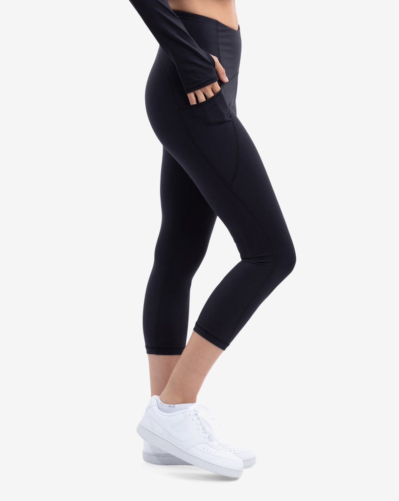Women wearing compression capri leggings in black. Side view showing pocket. (Style 6103) -BloqUV