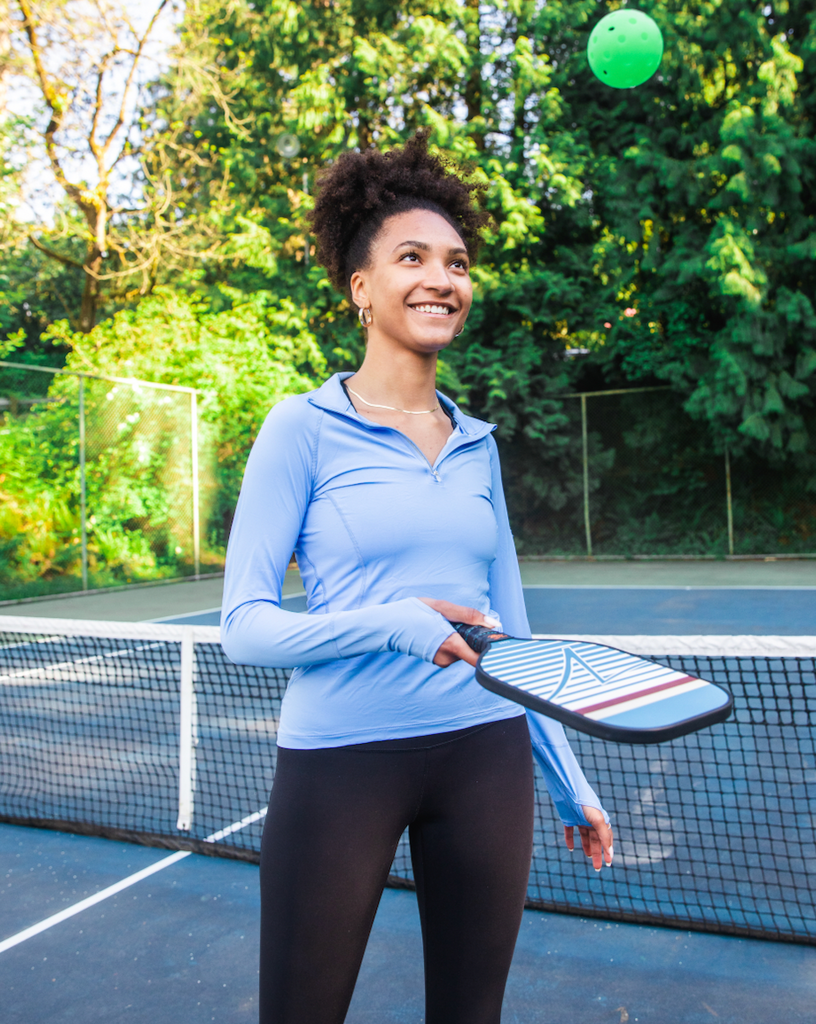 Women with pickleball racquet wearing indigo blue mock zip long sleeve top with black tights.  (Style 3001) - BloqUV